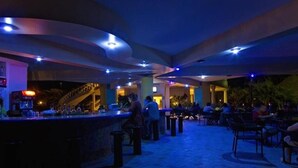 An indoor bar area with a curved counter, seating arrangements, and a staircase in the background.
