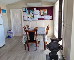 A dining area with a table set for four, surrounded by wooden chairs. A decorative black urn is placed on the floor beside the table. - Dream View  ~  lovely sea views! (James Well)