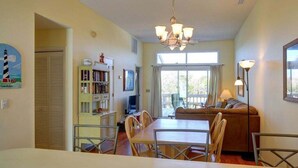 Un comedor con mesa y sillas, un sofá, una estantería y un televisor.