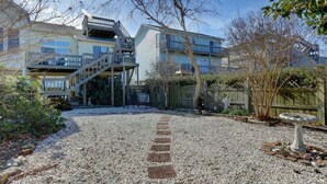 Un edificio de varios pisos, una escalera y un camino de grava que conduce a una terraza de madera.