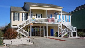 Un edificio de dos pisos con un balcón, una escalera y una puerta azul.