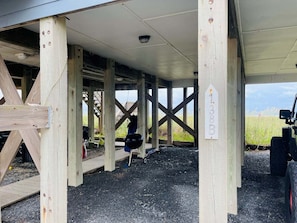 Un espace extérieur abrité, doté de poutres en bois, d’un barbecue et d’un panneau indiquant des numéros.