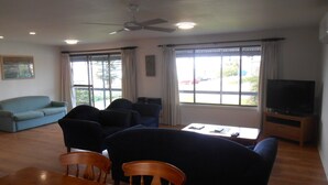 A living room with a sofa, chairs, a TV, and a dining table. - Roshy's Retreat ~ sea views off deck - Off Peak Special! (Point Turton)