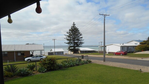 A view of a residential area with houses, a road, and a large tree. - Roshy's Retreat ~ sea views off deck - Off Peak Special! (Point Turton)