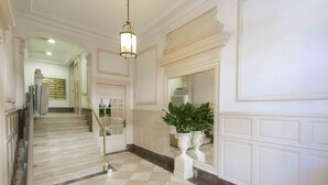 Un amplio pasillo con piso de mármol, una escalera y un espejo grande.