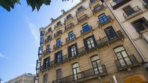 A multi-story building with balconies, a sign reading "INICIO," and a sign indicating "TODO A MITAD DE PRECIO."
