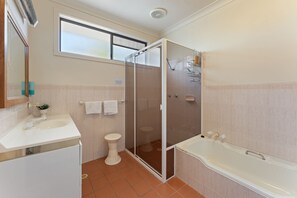 Een badkamer met douche, toilet, wastafel en bad.