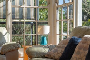 A room with a large window, a sofa, and a lamp.