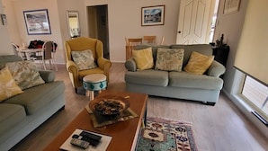 Uma sala de estar com dois sofás, uma mesa de centro e um espaço de jantar com uma mesa e cadeiras.