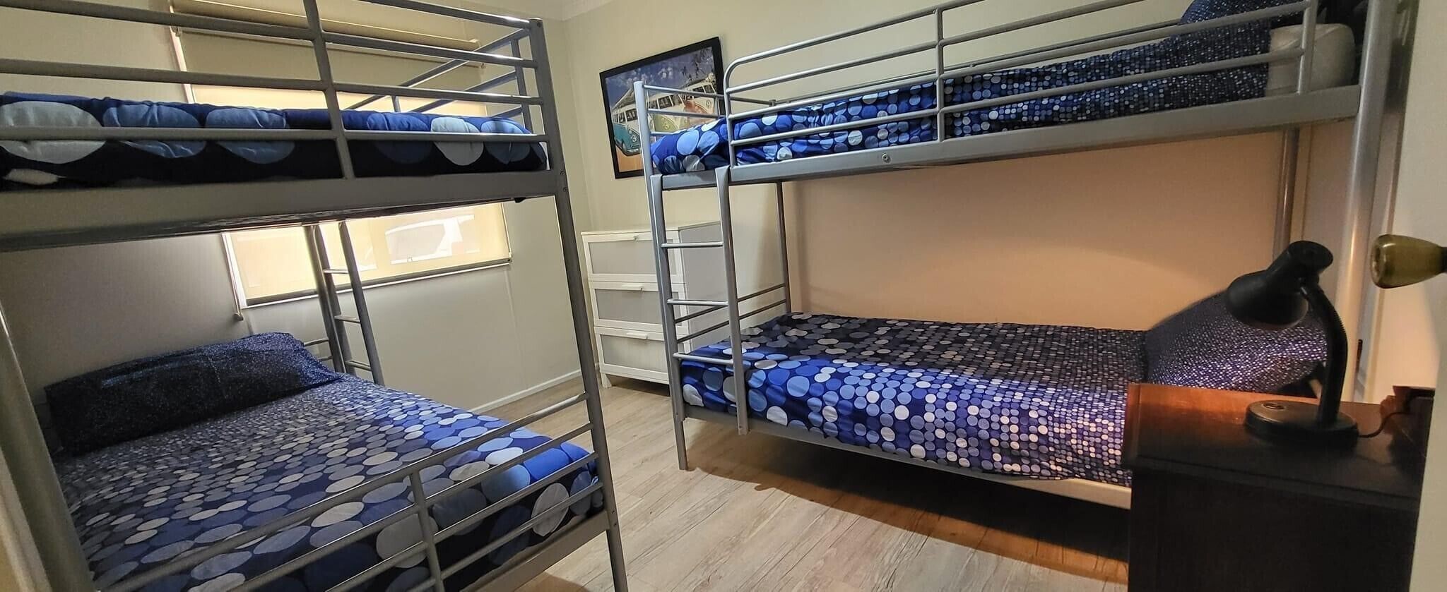 A dormitory room with bunk beds, a desk, and a lamp.