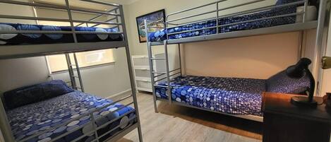 A dormitory room with bunk beds, a desk, and a lamp.