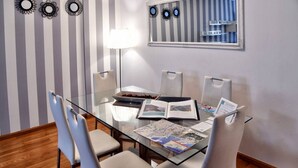 Un coin repas avec une table en verre, des chaises blanches et un mur à rayures agrémenté de miroirs décoratifs.