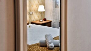 Une chambre d’hôtel avec un lit bien fait, une lampe de chevet et une petite table sur laquelle se trouve un bol.