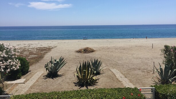 A beach with a clear view of the ocean, a sandy area with some plants, and a few people in the distance. - Ferruzzano portion of villa with stunning views and direct access to the sea (ferruzzano)
