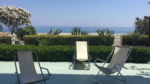 A patio with two lounge chairs facing a beach. - Ferruzzano portion of villa with stunning views and direct access to the sea (ferruzzano)
