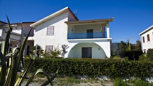 A two-story building with a balcony, a large arch over the entrance, and a clear blue sky. - Ferruzzano portion of villa with stunning views and direct access to the sea (ferruzzano)
