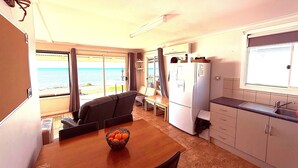 Eine kleine Küche mit Essbereich, einem Kühlschrank und Blick auf den Strand.