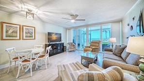 A spacious living room with a large TV, comfortable seating, and a view of the outdoors.
