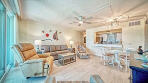 A living room with a sofa, armchair, and a dining area with chairs and a table. - LaPlaya 106A-Beach front!  (Longboat Key)