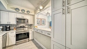 A modern kitchen with white cabinetry, a built-in microwave, a coffee maker, and a stove. - LaPlaya 106A-Beach front!  (Longboat Key)