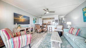 A living room with a sofa, armchairs, a coffee table, and a dining area with chairs and a table.