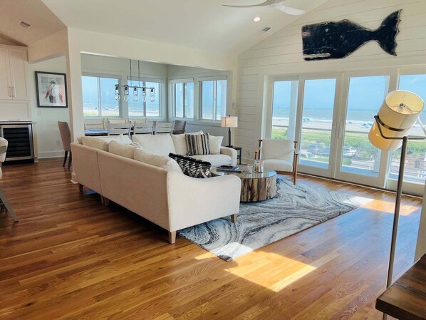 A modern living room with a sofa, coffee table, and large windows offering a view of the ocean.