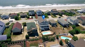 Un quartier résidentiel situé sur la côte, avec des maisons, une piscine et une plage en arrière-plan.