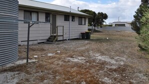A single-story mobile home with a metal roof, a small porch, and a visible staircase leading to the entrance.
