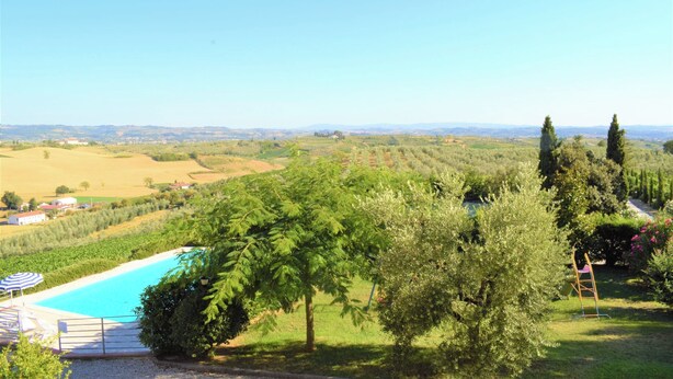 A pool surrounded by lush greenery and a view of distant hills. - Agriturismo Luggiano Apartment "AIA" (Vinci)