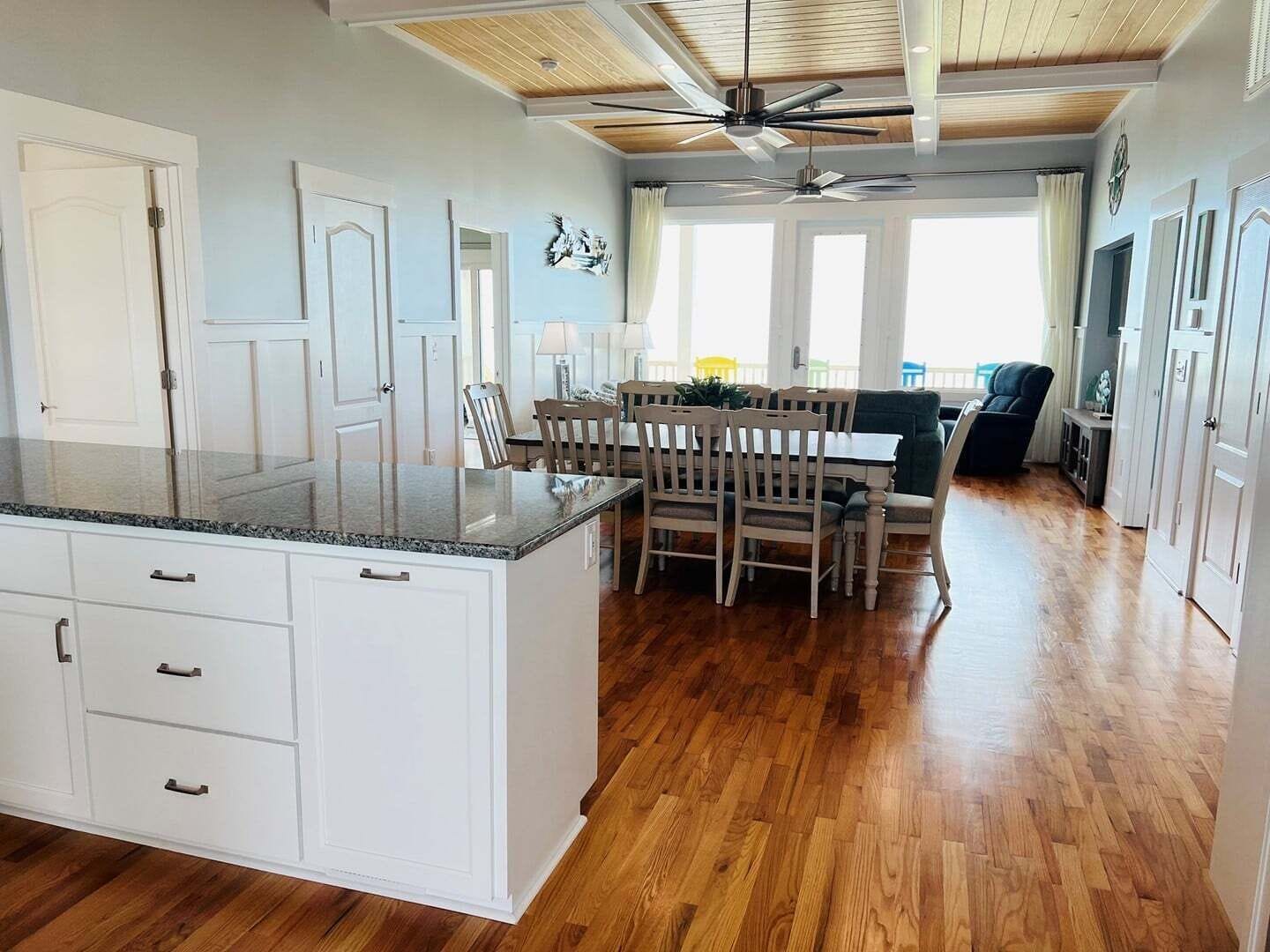 A spacious kitchen with a central island, wooden flooring, and a ceiling fan.
