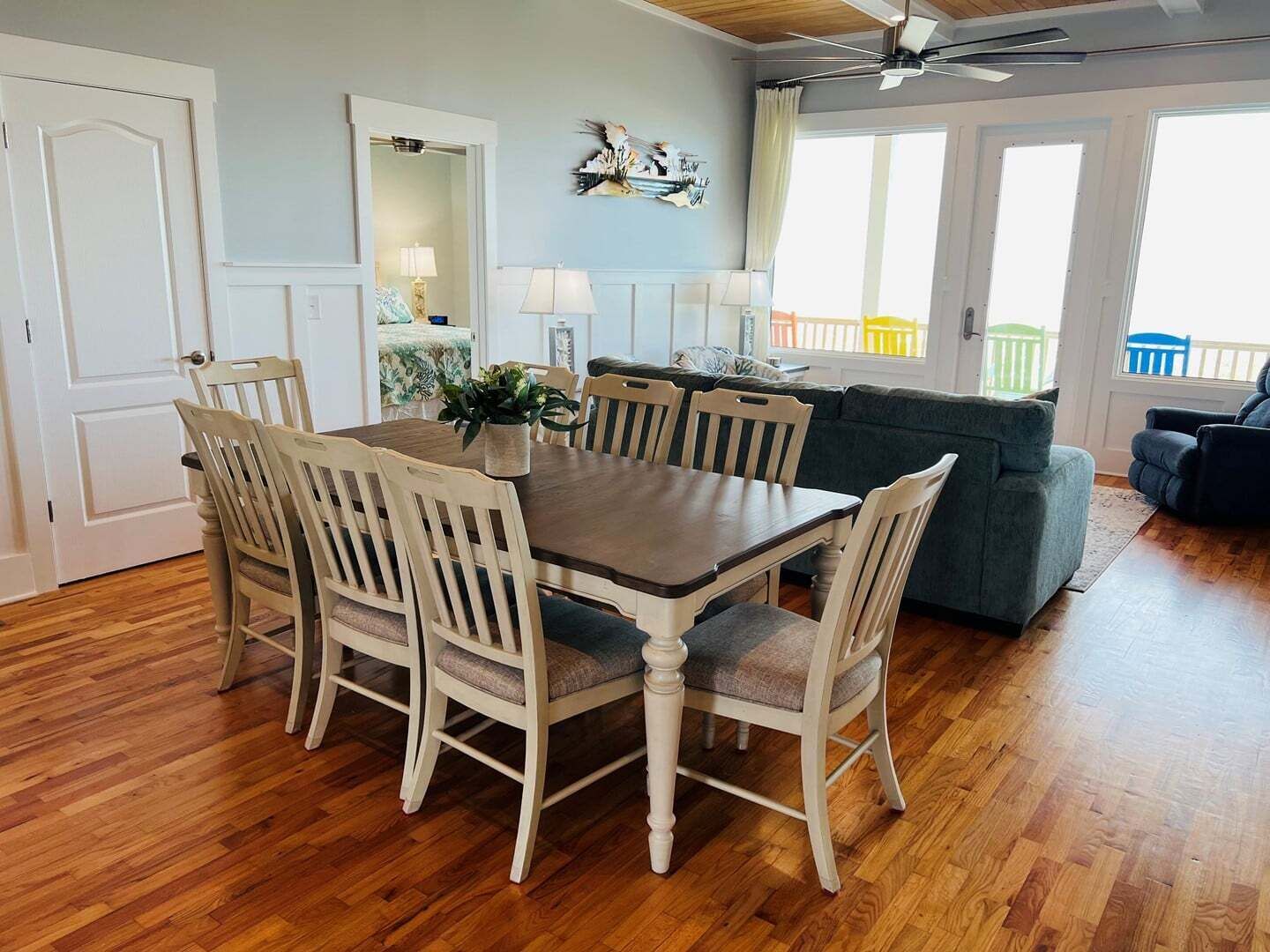 A dining area with a wooden table and chairs, a sofa, and a ceiling fan.