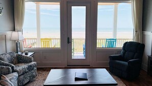 Une pièce avec vue sur la plage, comprenant un canapé, un fauteuil, une table et une lampe.