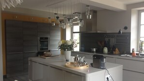A modern kitchen with a central island, stainless steel appliances, and pendant lighting. - 5-hectare family estate with swimming pool near Bourges (Berry-Bouy)