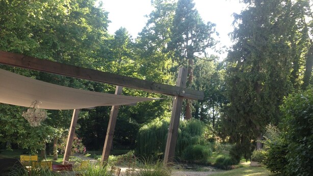 A garden pathway with a wooden pergola and potted plants. - 5-hectare family estate with swimming pool near Bourges (Berry-Bouy)