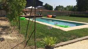A swimming pool with a tiled deck, surrounded by grass and a few potted plants. - 5-hectare family estate with swimming pool near Bourges (Berry-Bouy)