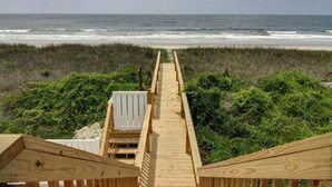 Une promenade en bois menant à la plage, entourée de verdure.
