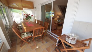 Een eethoek met een houten tafel, stoelen en een klein karretje met een zilveren pot.
