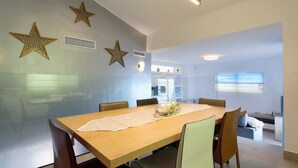 Ein moderner Essbereich mit einem Holztisch, Stühlen und dekorativer Wandkunst mit Sternenmotiven.