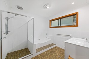 Een badkamer met een douche, bad en wastafel.