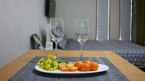 Habitación de hotel con una cama, dos copas de vino vacías, un plato de fruta y una mesita.