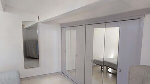 A room with a bed, a wardrobe with a mirror, and a small table with a tablecloth. - Bright seafront house with superb sea view, 2 free parking spaces. (Cap d'Agde)