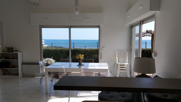 A modern kitchen with a large island, white cabinetry, and a view of the sea. - Bright seafront house with superb sea view, 2 free parking spaces. (Cap d'Agde)