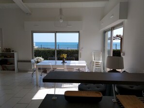 A modern kitchen with a large island, white cabinetry, and a view of the sea.