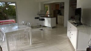 A modern kitchen with white cabinetry, a central island, and a dining area with a glass table and chairs. - Bright seafront house with superb sea view, 2 free parking spaces. (Cap d'Agde)