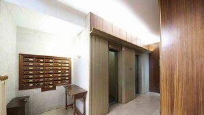 A hallway with a wooden panel wall, a small wooden table, and an elevator. - Niza | The Rentals Collection (San Sebastián)