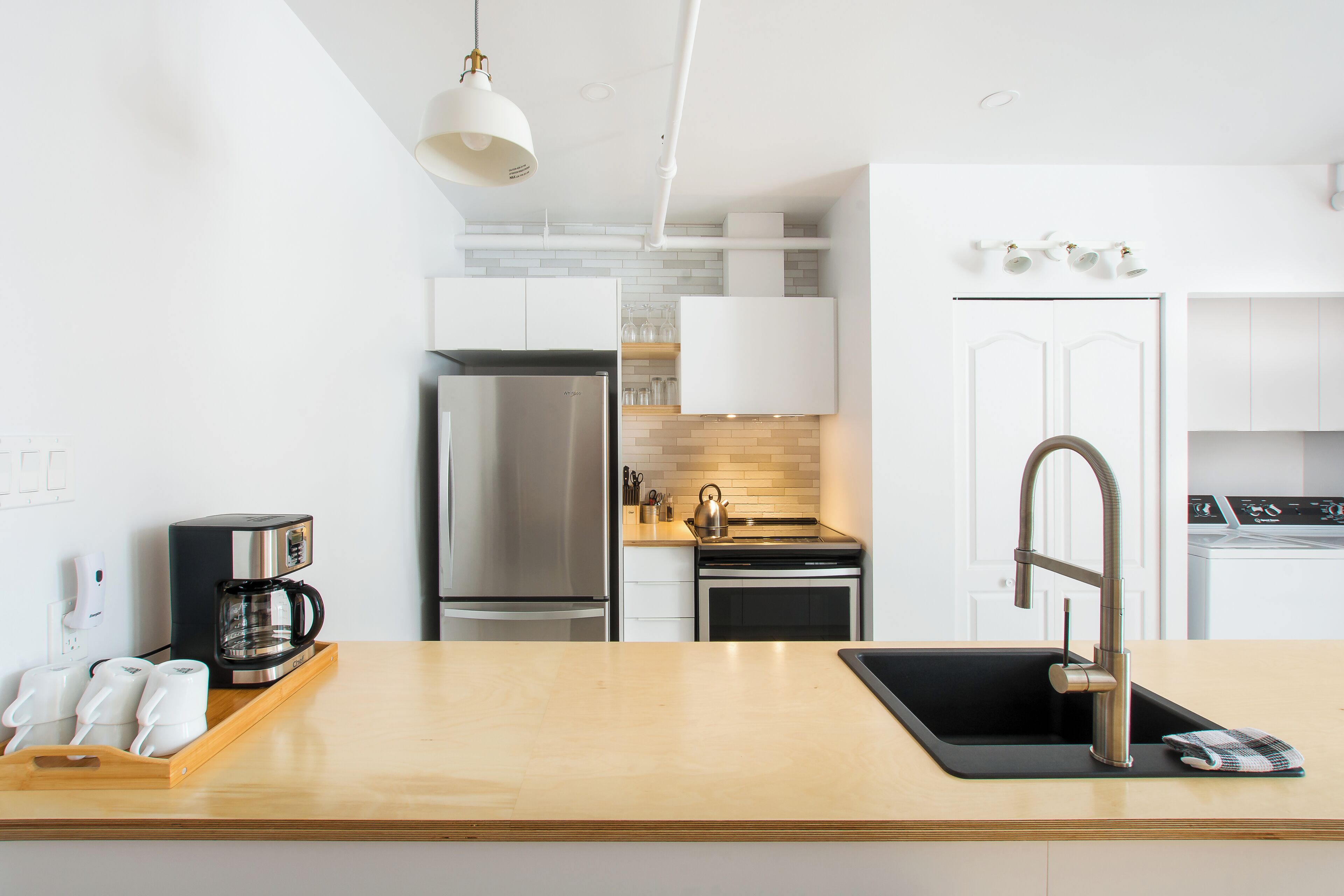A modern kitchen with a stainless steel refrigerator, a coffee machine, and a sink with a modern faucet.