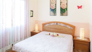 A neatly made bed with a floral bedspread, two bedside lamps, and a wooden headboard. - Eveten 1 - apartment for 4, in town centre, 500 metres from the beach, with parking (Diano Marina)