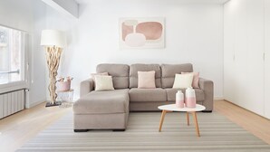 A modern living room with a sectional sofa, a small round table, and a large abstract painting on the wall.