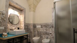 Een badkamer met een wastafel, spiegel, bidet en een koelkast.