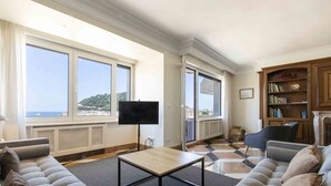 A living room with a sofa, a coffee table, a flat-screen TV, and a bookshelf.